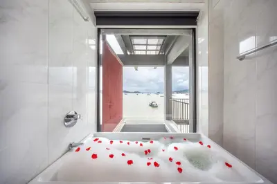 a bath tub with red flowers on it in a bathroom at SHIN Arch39 Phuket Beach Front - SHA Plus in Chalong