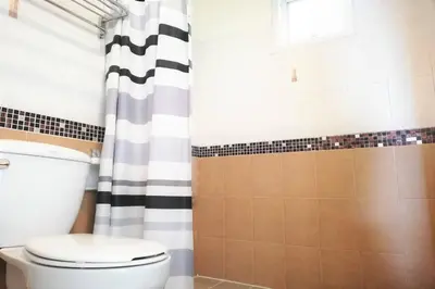 a bathroom with a toilet and a shower curtain at Andaman Place in Thalang