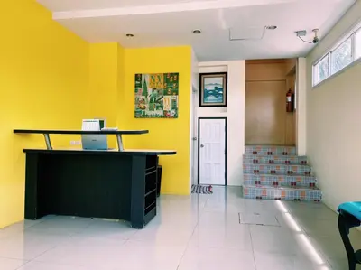 an empty lobby with yellow walls and a desk at Andaman Place in Thalang