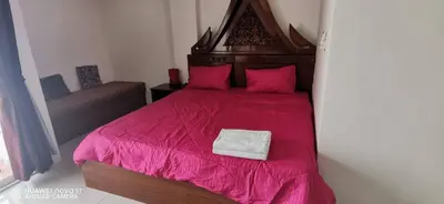a bedroom with a red bed with pink sheets at Sure Guesthouse in Kamala Beach