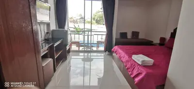 a small bedroom with a red bed and a balcony at Sure Guesthouse in Kamala Beach
