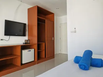 a bedroom with a tv and a bed with blue pillows at Sure Guesthouse in Kamala Beach
