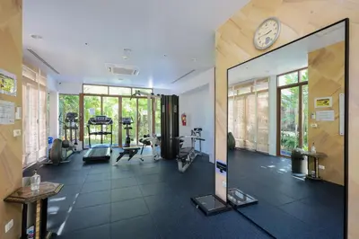 a gym with a large mirror and a clock on the wall at Kata gardens 2 bedroom near Kata beach 3B in Kata Beach