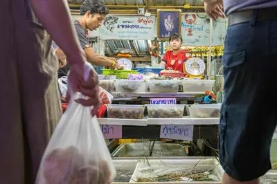 a group of people standing in a market selling food at NaiHarn Pearl Condo - Pets Friendly! in Nai Harn Beach