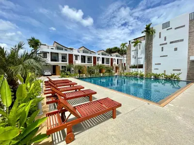 a row of wooden benches next to a swimming pool at Genesis Villas in Rawai Beach