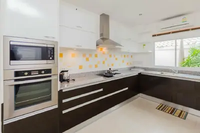 a kitchen with black and white cabinets and a microwave at Genesis Villas in Rawai Beach