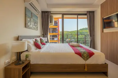 a bedroom with a bed and a balcony at NaiHarn Pearl condo by Holy Cow, 1-BR, courtyard view in Nai Harn Beach
