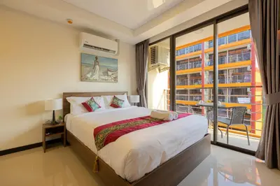 a bedroom with a bed and a large window at NaiHarn Pearl condo by Holy Cow, 1-BR, courtyard view in Nai Harn Beach