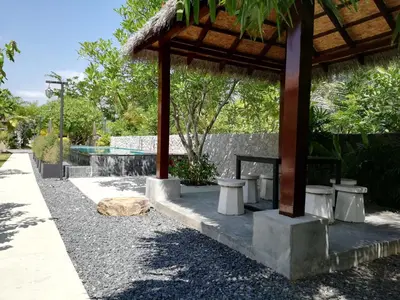 a pavilion with a table and stools next to a pool at Laemsai Resort in Thalang