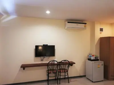 a room with two chairs and a tv on the wall at Laemsai Resort in Thalang