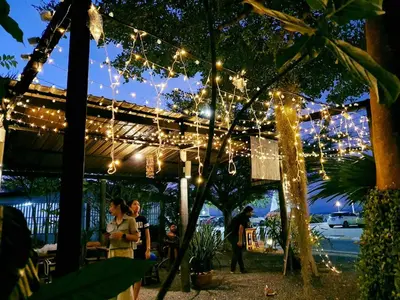 a group of people standing under a pergola with lights at Laemsai Resort in Thalang