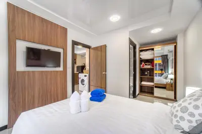 a bedroom with a white bed with a tv on the wall at SOLA Condo 1BR Tropical View NBC Nai Harn Nai in Rawai Beach