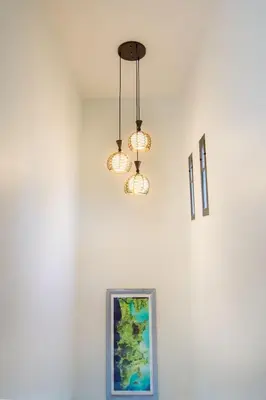 two lights hanging from a white wall with a picture at Koh Sirey Beachfront Pool Villa in Phuket Town