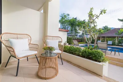 a patio with two chairs and a table and a pool at Hill Myna Holiday Park & Cafe in Bang Tao Beach