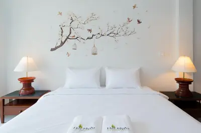 a bedroom with a white bed with two lamps at Hill Myna Holiday Park & Cafe in Bang Tao Beach