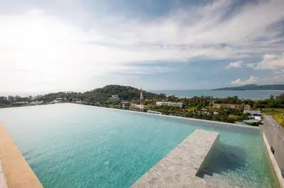 a large swimming pool with a view of the water at Sea View Panora Surin by Holy Cow, 1-BR in Surin Beach