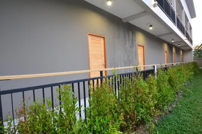 a fence in front of a building with plants at The Grey House Palai Phuket in Chalong