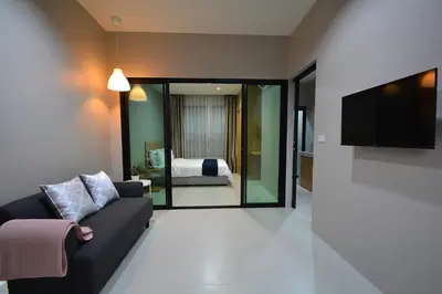 a living room with a couch and a flat screen tv at The Grey House Palai Phuket in Chalong