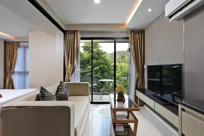 a bedroom with a bed and a living room at Panora Surin by Holy Cow, 1-BR, mountain view in Surin Beach