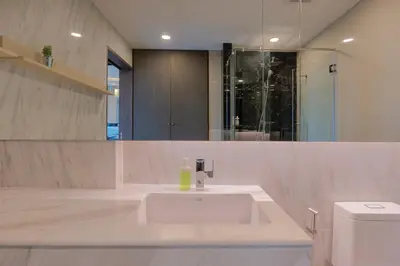 a white bathroom with a sink and a toilet at Panora Surin by Holy Cow, 1-BR, mountain view in Surin Beach