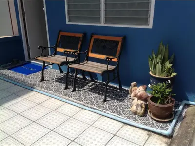 two chairs sitting next to a blue wall with plants at Phuket Town Budget House - Aircon Room #1 in Ban Lo Long