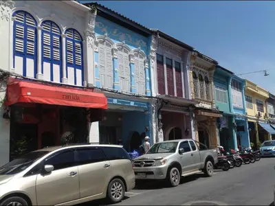 a street with cars parked in front of buildings at Phuket Town Budget House - Aircon Room #1 in Ban Lo Long
