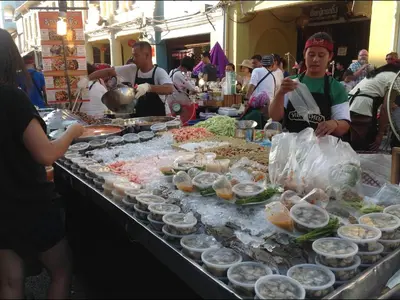 a group of people standing around a buffet of food at Phuket Town Budget House - Aircon Room #1 in Ban Lo Long