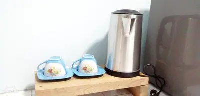 a coffee maker sitting on a wooden stand with two blue plates at Khao Thong Home Stay in Krabi town