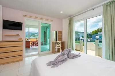 a bedroom with a bed with a television and a balcony at Kata Hill Sea View Hotel in Kata Beach