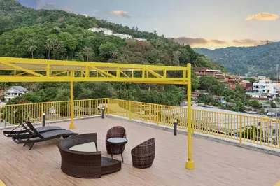 a yellow railing on a deck with chairs and tables at Dome Kata Resort in Kata Beach