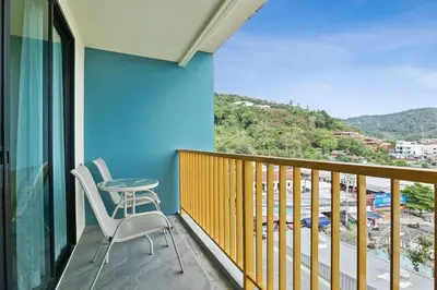 a balcony with two chairs and a view of a city at Dome Kata Resort in Kata Beach