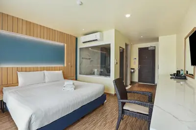 a hotel room with a bed and a chair at Dome Kata Resort in Kata Beach