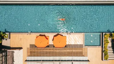 a swimming pool with a bench and a person in the water at Wekata Luxury in Kata Beach