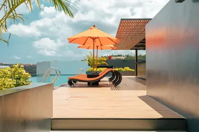 a patio with a table and an umbrella and a bench at Wekata Luxury in Kata Beach