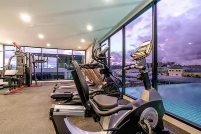 a gym with a row of treadmills and a swimming pool at Wekata Luxury in Kata Beach