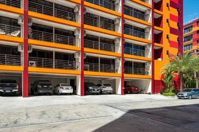an orange building with cars parked in the parking lot at Naiharn Pearl Condo Hotel by VillaCarte in Nai Harn Beach