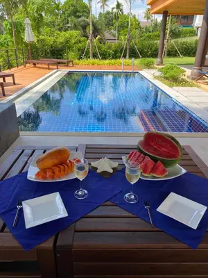 a table with food and drinks next to a swimming pool at Villa Tango Victoria Resort, Koh Yao Noi in Ko Yao Noi