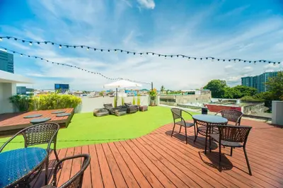 a deck with chairs and tables on a roof at PERA SPACE Capsule Hotel in Phuket Town