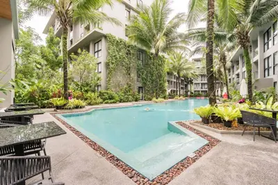 a swimming pool in a courtyard with palm trees at Diamond CONDO by VС in Bang Tao Beach