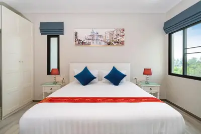 a bedroom with a large white bed with blue pillows at The Title Residencies Naiyang Beach in Nai Yang Beach