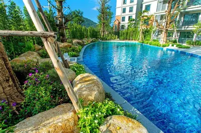 a swimming pool with rocks and a building at The Title Residencies Naiyang Beach in Nai Yang Beach
