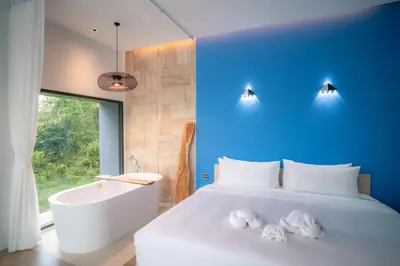 a bedroom with a white bed and a tub and a bath tub at Chomdao Maikhao in Mai Khao Beach