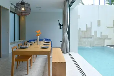 a dining room with a table and a swimming pool at Chomdao Maikhao in Mai Khao Beach