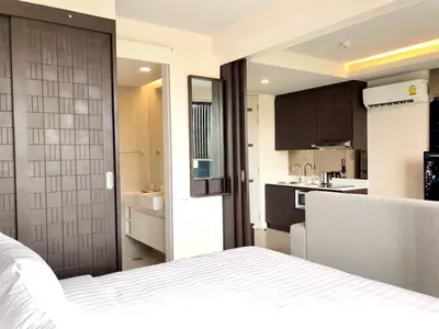 a bedroom with a white bed and a kitchen at Aristo Resort Surin Beach S03 in Surin Beach