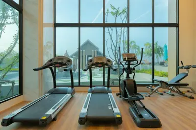 a gym with treadmills and ellipticals in front of a window at Sea View 1-BR 36 m2 Panora Surin by Holy Cow in Surin Beach