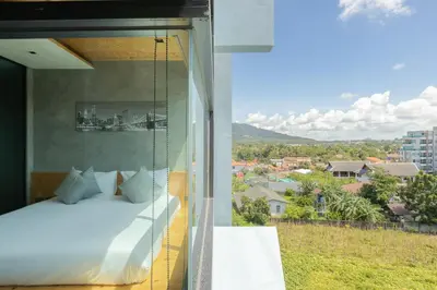 a bedroom with a bed and a view of a city at Relife Windy by Holy Cow, studio with stunning country view in Nai Harn Beach