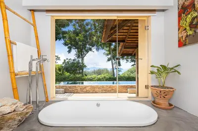 a large white bath tub in a bathroom with a window at SAMSAM Yao Noi - ANDAMAN MAGIC & ART VILLAS in Ko Yao Noi
