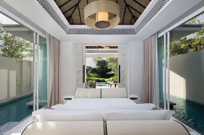 a bedroom with white beds and a swimming pool at Banyan Tree Krabi in Tab Kaek Beach