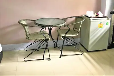 a glass table and two chairs next to a small refrigerator at Nasa Hotel in Phuket Town