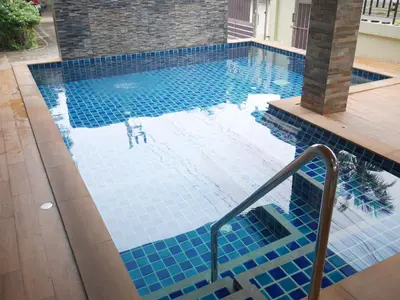 a swimming pool with a blue tile floor and stairs at Nasa Hotel in Phuket Town
